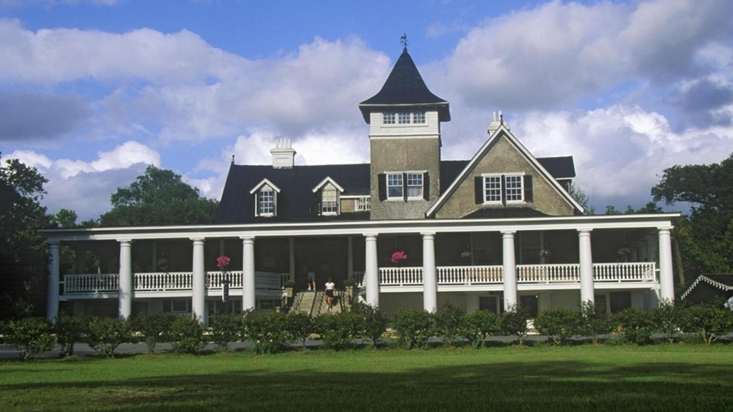 a small clock tower in front of a house with W. H. Stark House in the background
